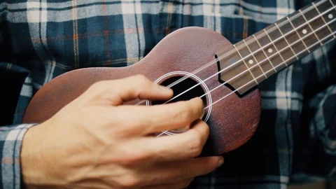 Close up hand playing ukulele. Man touches strings. Wood ukulele Stock Footage 120300103
