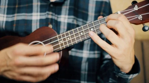 Close up hand playing ukulele. Man touches strings. Wood ukulele Stock Footage 120300160