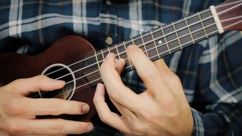 Close up hand playing ukulele. Man touches strings. Wood ukulele Stock Footage 120300168