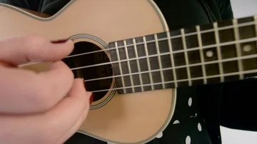 Close of a hand plucking ukulele strings Stock Footage 85363598