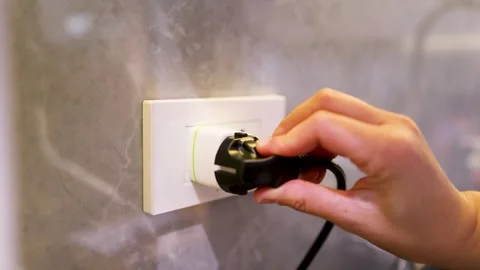 Close up hand plugging black electric power cord into universal travel adap.. Stock Footage 333300648