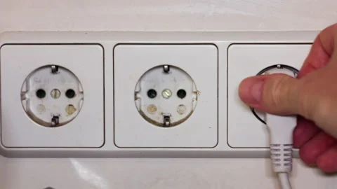 Close-up of Hand Plugging Electrical Cable into a Triple Wall Power Socket 库存影片 337429919