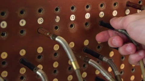 Close up of a hand plugging jacks in holes of a historical switchboard, Vídeo Stock 132805252