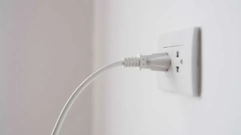 Close up of hand plugging in power cord and unplugging into socket to save en Stock Footage 221533127