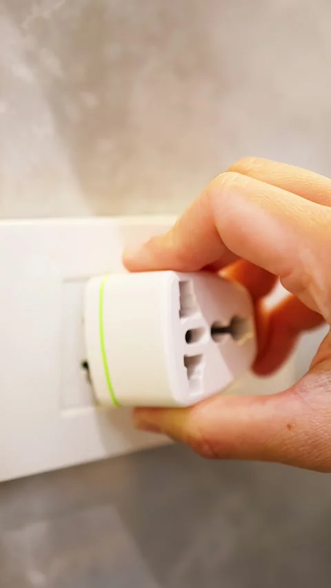 Close Up of Hand Plugging Universal Travel Adapter into Wall Socket Stock Footage 333165177