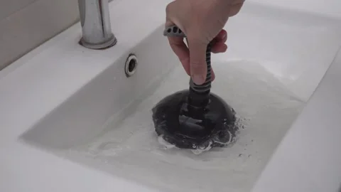 Close-up of hand with plunger clearing a blockage in a bathroom sink Stock Footage 263189031