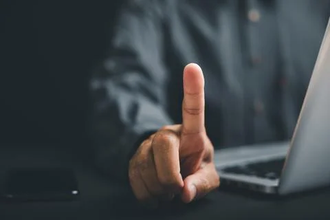 Close-up of a hand pointing up with a laptop in the background. The image h.. Stock Photos