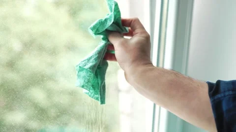 Close up of a hand polishing a wet window pane with a green microfiber rag .. 動画素材 340159543