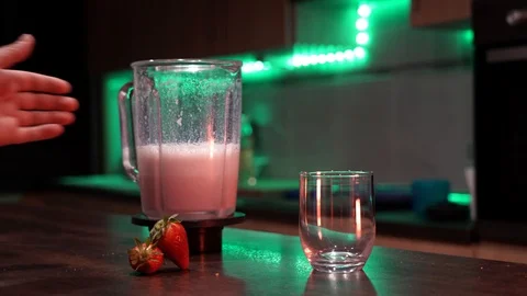 Close up of a hand pouring fresh made strawberry milkshake on a glass and two 스톡 동영상 129043442