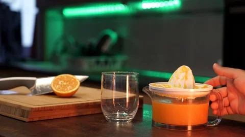 Close up of a hand pouring fresh made orange juice into a glass on a kitchen  스톡 동영상 129043647