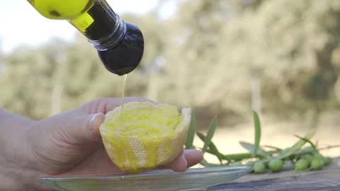 Close up of a hand pouring golden extra virgin olive oil onto a piece of fresh Stock Footage 343321745
