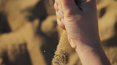 Close up of hand pouring sand of beach with sea background. Sand spills out of Stock Footage 306690913