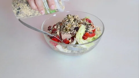 Close up of hand pouring various seeds into a salad Stock Footage 111587655