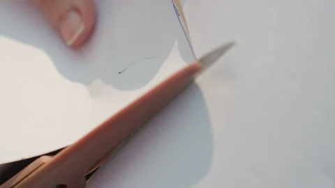 Close up of hand precisely cutting paper with scissors revealing clean edges and Video stock 345975720