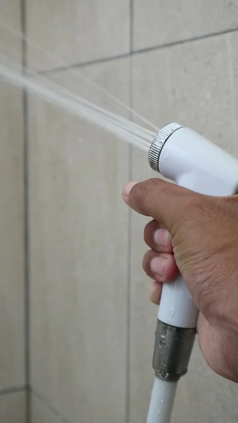 Close up hand pressing bidet sprayer trigger in bathroom hygiene routine Stock Footage 333377807