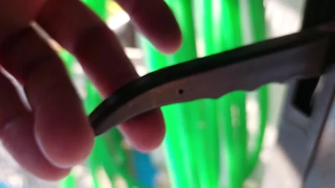 Close-up of a hand pressing a black plastic lever handle with a green garden hos Stock Footage 335646448