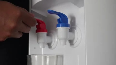 Close up of hand pressing a blue tap on a water dispenser machine to pour fresh  Video stock 337761070