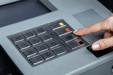 Close-up of a hand pressing a button on a modern ATM keypad, showcasing the.. Stock Photos