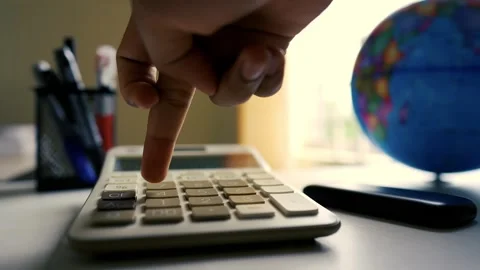 Close-up of a hand pressing buttons on a calculator with a globe in the bac.. Stock Footage 318056565