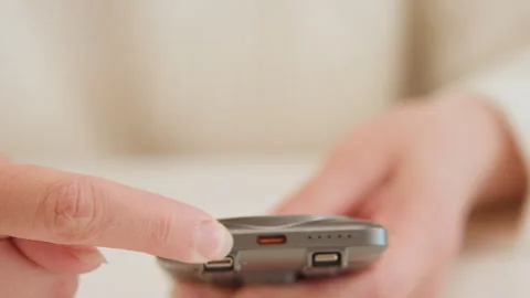 Close-up hand pressing buttons on compact handheld remote device with visible Stock Footage 345653249
