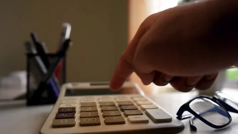 Close-up of a hand pressing a calculator button on a desk Stock Footage 317737015