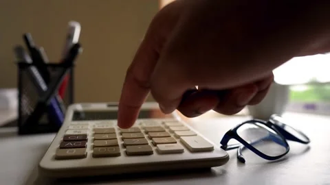 Close-up of a hand pressing a calculator button on a desk Stock Footage 317737020