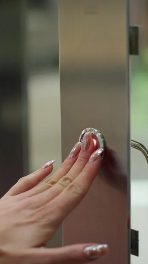 Close-Up Hand Pressing Elevator Button on Sleek Metallic Panel Stock Footage 310574806