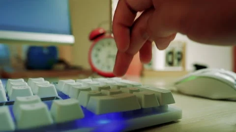 Close-up of a hand pressing a key on a backlit keyboard with a clock in the.. Stock Footage 316901983