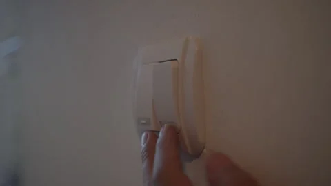 Close-up of a hand pressing a light switch on a white wall Stock Footage 339196187