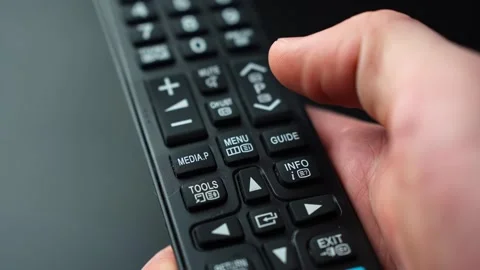 Close-up of a hand pressing the MENU button on a TV remote control, opening Stock Footage 329479704