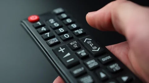Close-up of a hand pressing the mute button on a TV remote control, silencing Stock Footage 329471461