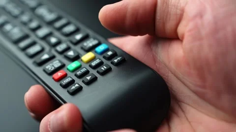 Close-up of a hand pressing the pause button on a TV remote control, stopping Stock Footage 332239435