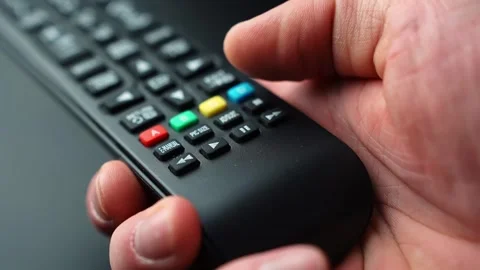 Close-up of a hand pressing the PLAY button on a TV remote, resuming 库存影片 331318624