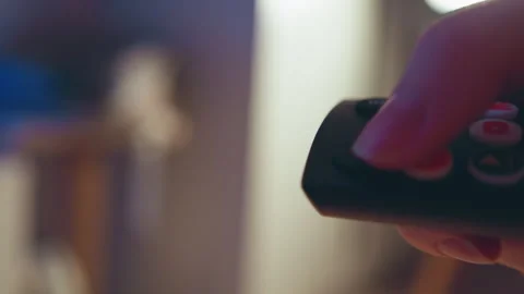 Close-up hand pressing remote control button with warm indoor bokeh background Stock-Footage 345656000