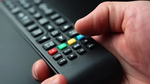 Close-up of a hand pressing the rewind button on a TV remote control, skipping Stock Footage 329479523