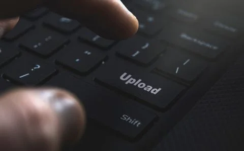 Close-up of a hand pressing the upload button on keyboard. Illustrating the Stock Photos