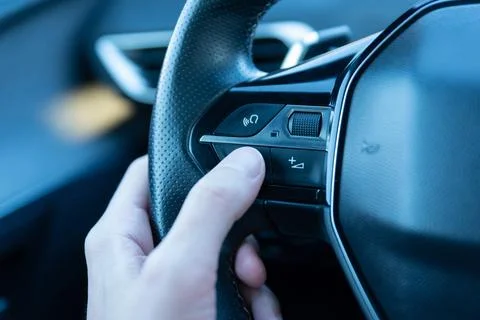 Close-up of a hand pressing the voice command button on a steering wheel Stock Photos