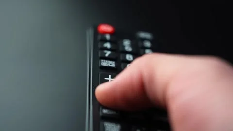 Close-up of a hand pressing the volume down button on a TV remote control Stock Footage 329479852
