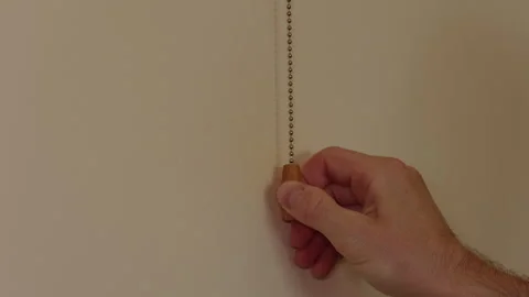 Close-up of a hand pulling a beaded chain switch to turn on the light Vidéo 342390663