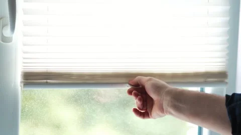 Close up of a hand pulling down white pleated window blinds to block light Vídeo Stock 340159297