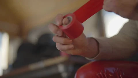 Close-up of hand pulling red tape Stock Footage 346055943