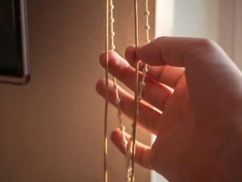 Close up hand pulling the rope to close and open jalousie at home Foto stock