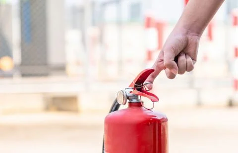 Close up of a hand pulling the safety pin of a fire extinguisher Stock Photos