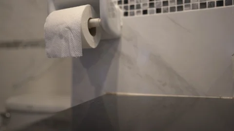 Close up hand pulling tissue paper in roll on wall of toilet Stock Footage 122883830