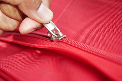 Close up of a hand pulling a zipper on red fabric Stock Photos