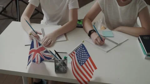 Close up of a hand of pupils writing in a class. British and American flag on a Stock Footage 134447752