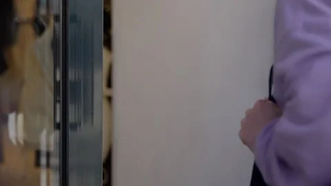 Close-up of a hand in a purple sleeve pulling a door handle, focusing on the Vidéo 276940762