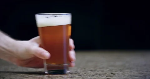 Close up of a hand pushing a pint of beer on a bar into frame in slow motion 4k Stock Footage 104458443