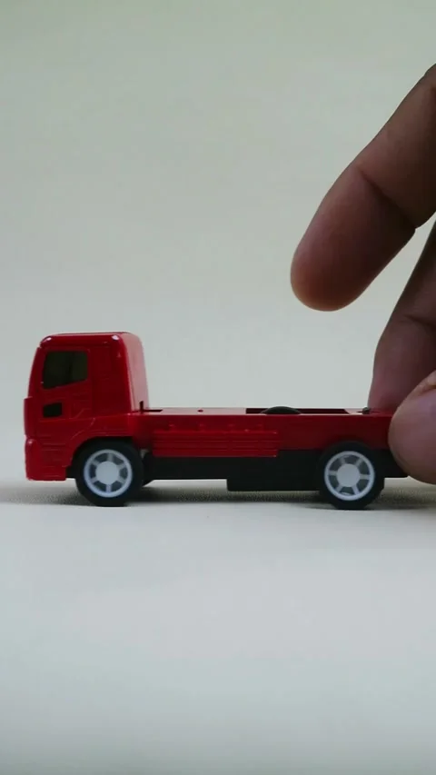 Close Up Hand Pushing Red Toy Truck on Clean Minimal Background Stock Footage 334022154