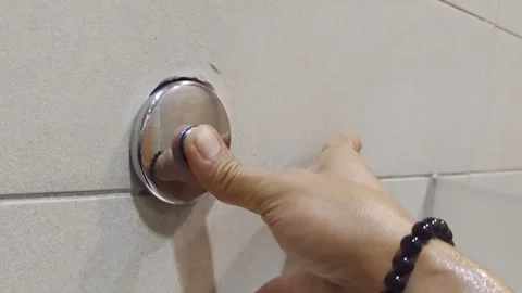 Close up of hand pushing a silver dual flush button on a white tiled wall Video stock 328714072